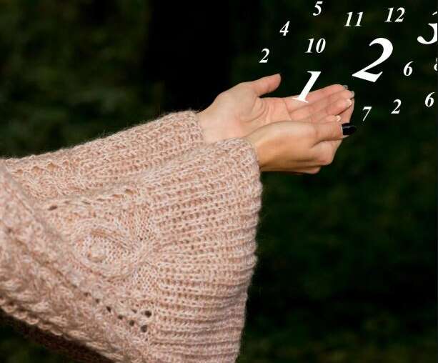 Hand in warmem Strick, goldene Partikel – Symbolbild für Geldfluss, Wert & bewusste Ausrichtung.