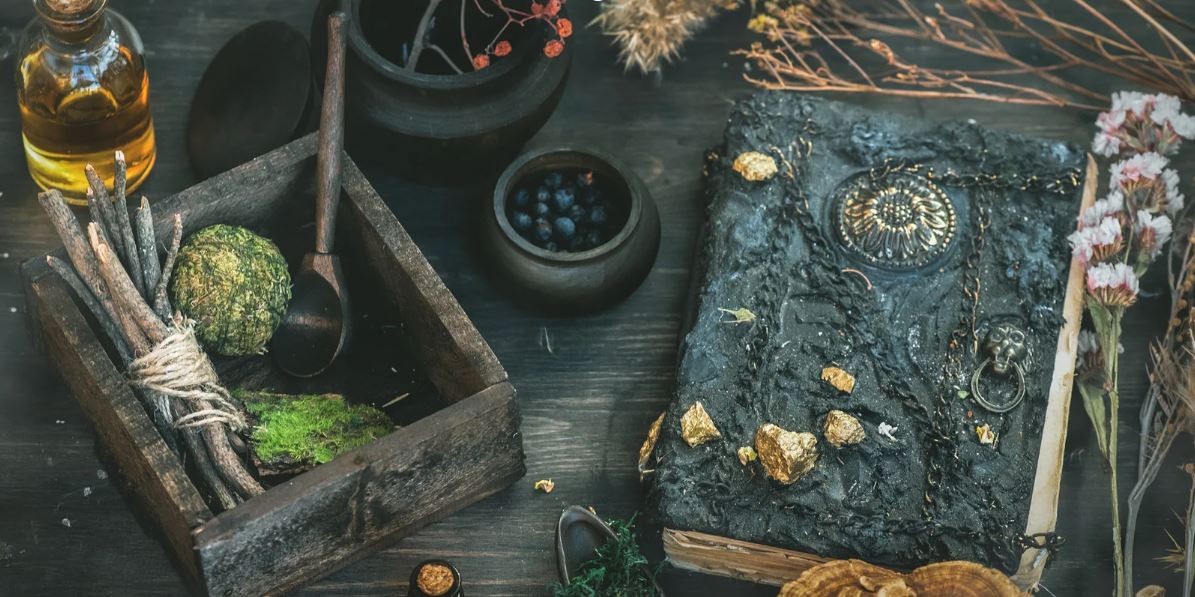 Ritualplatz mit Notizbuch, Kräutern, Räucherwerk und kleinen Schalen auf dunklem Holztisch