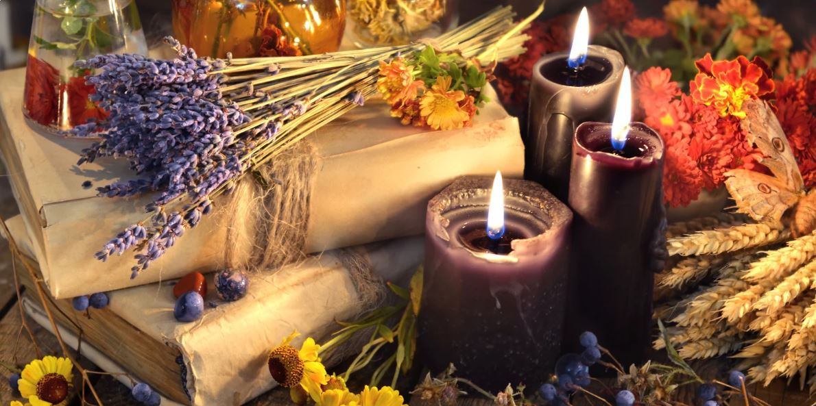 Ritueller Herbstaltar mit brennenden Kerzen, Lavendel, Büchern und getrockneten Blüten